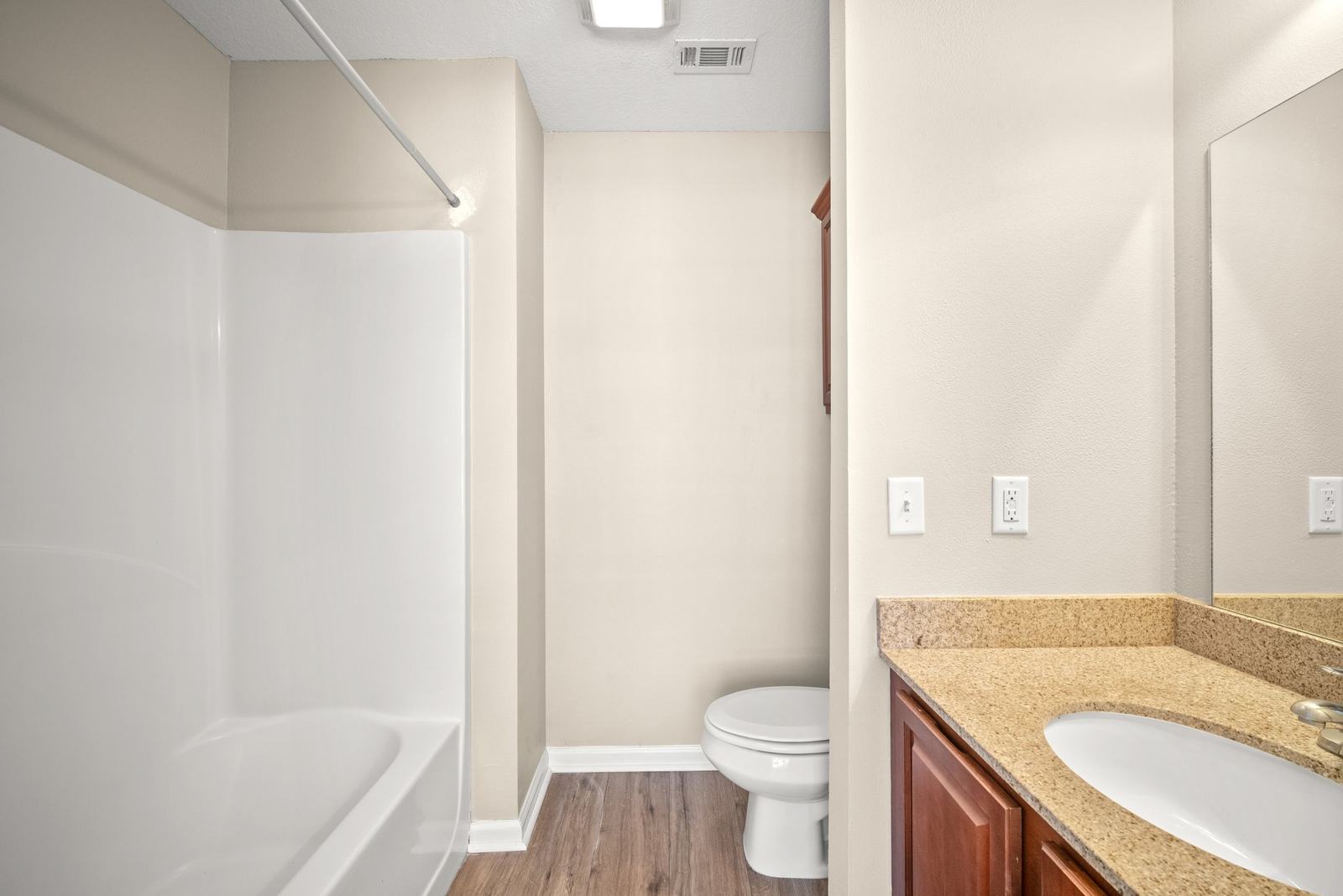 Full bath with tub, granite vanity and wood-look floor